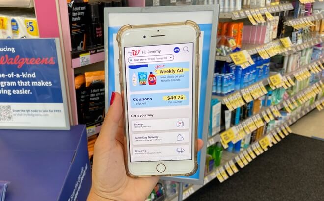 A hand holding a mobile phone with the Walgreens app opened. The person in in a Walgreens store.